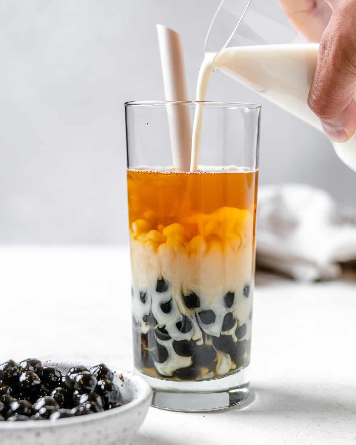 Einfacher Veganer Bubble Tea 2 process shot of pouring creamer into glass against a light background