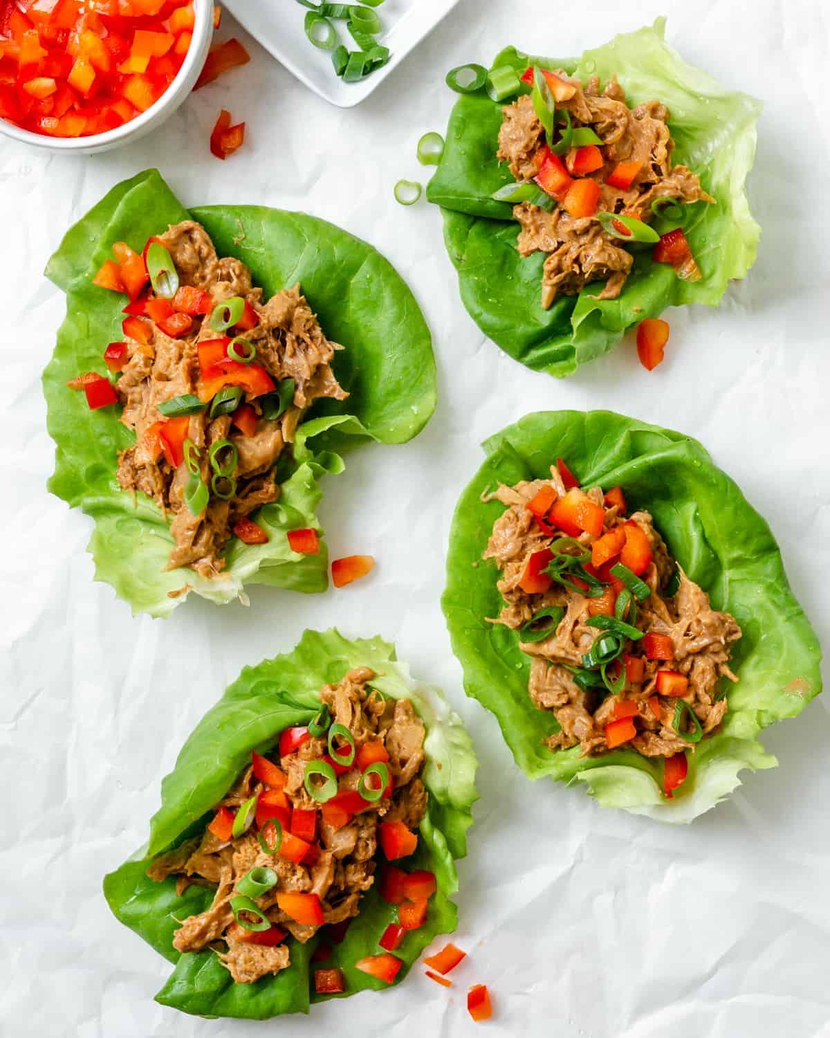 Jackfrucht-Salatwickel 2 Mehrere fertige Jackfrucht-Salat-Wraps auf einer weißen Fläche ausgebreitet