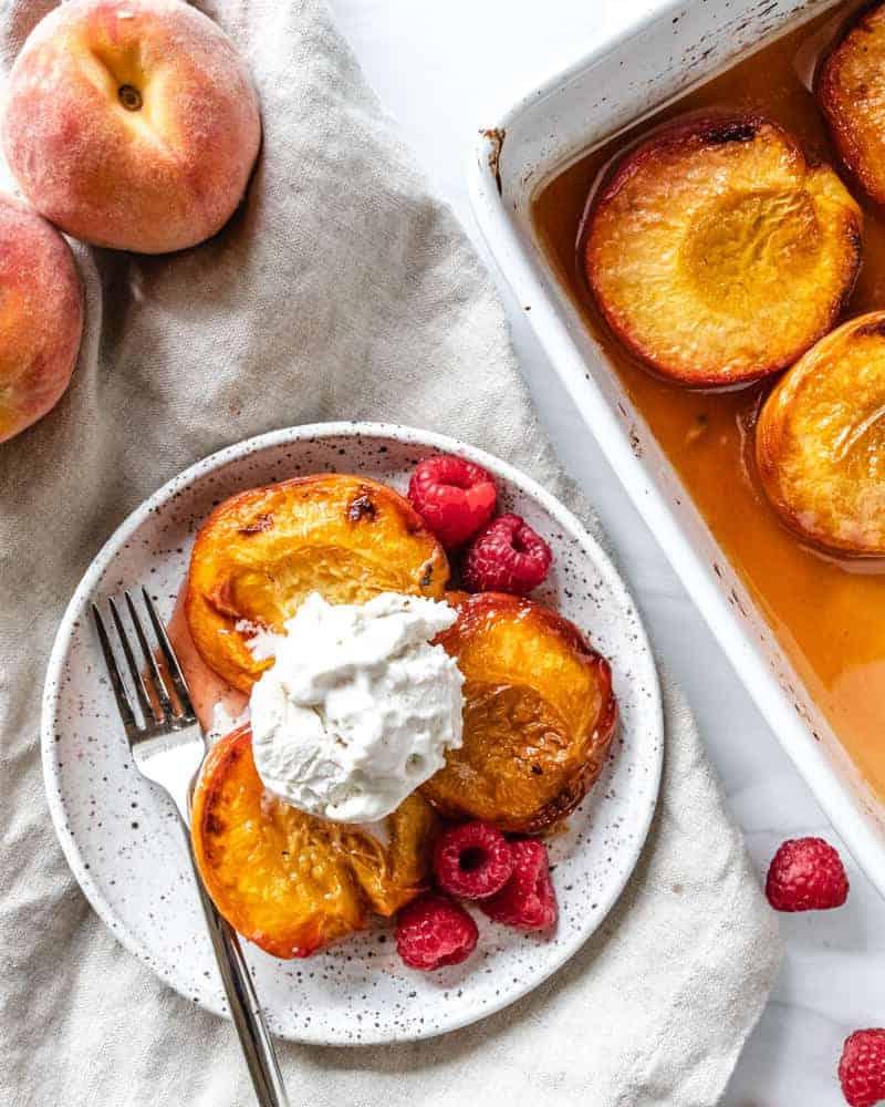 Gebackene Pfirsiche 2 Geröstete Pfirsiche mit Himbeeren und Eiscreme auf weißem Hintergrund