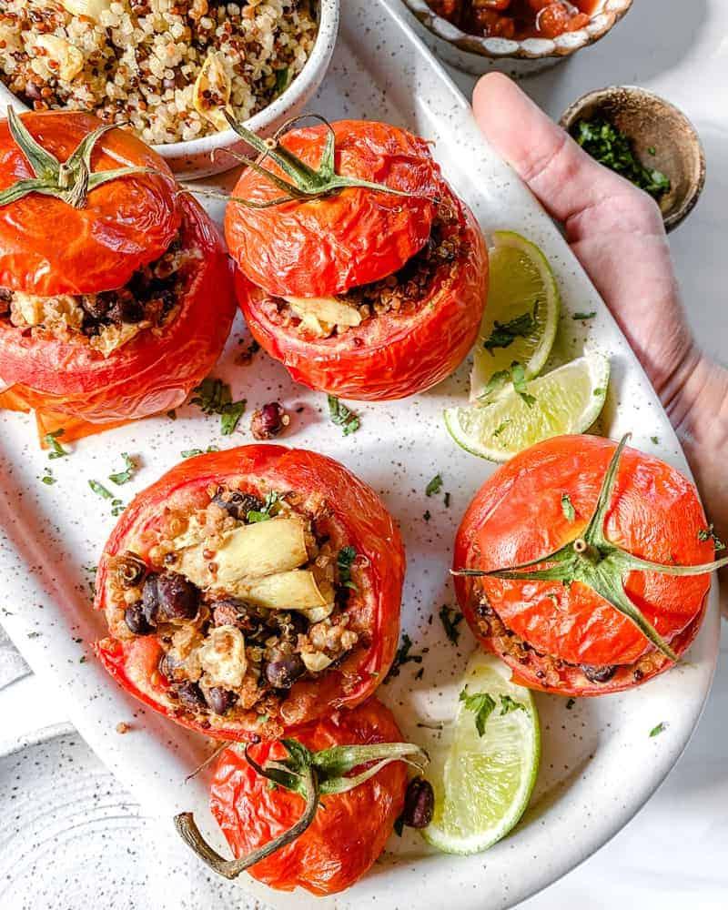 Gefüllte Tomaten 2 Fertige gefüllte Tomaten auf einem weißen Teller vor weißem Hintergrund