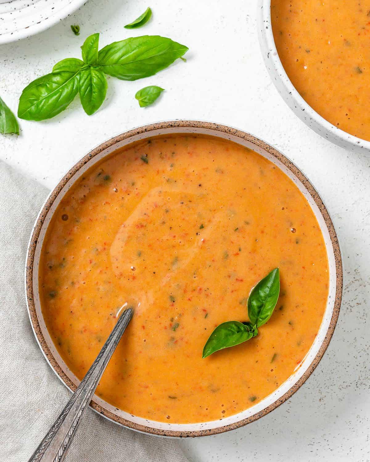 Cremige geröstete rote Paprikasuppe 2 Zwei Schalen mit fertiger cremiger gerösteter roter Paprika Suppe auf hellem Untergrund