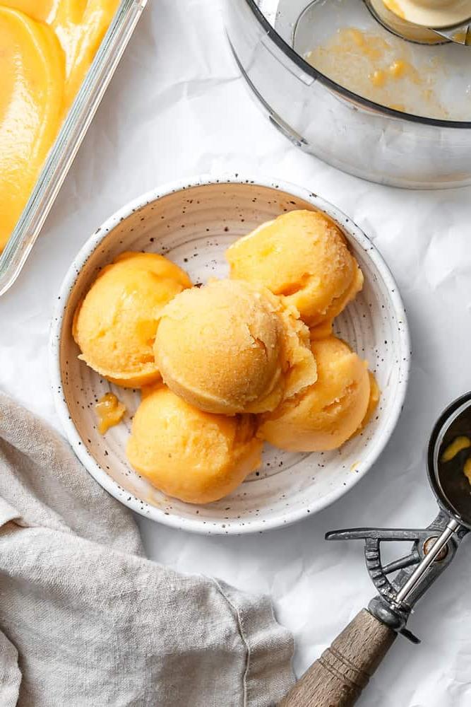 **Pfirsich Sorbet** 2 Eine weiße Schale mit 5 Kugeln Pfirsich Sorbet.