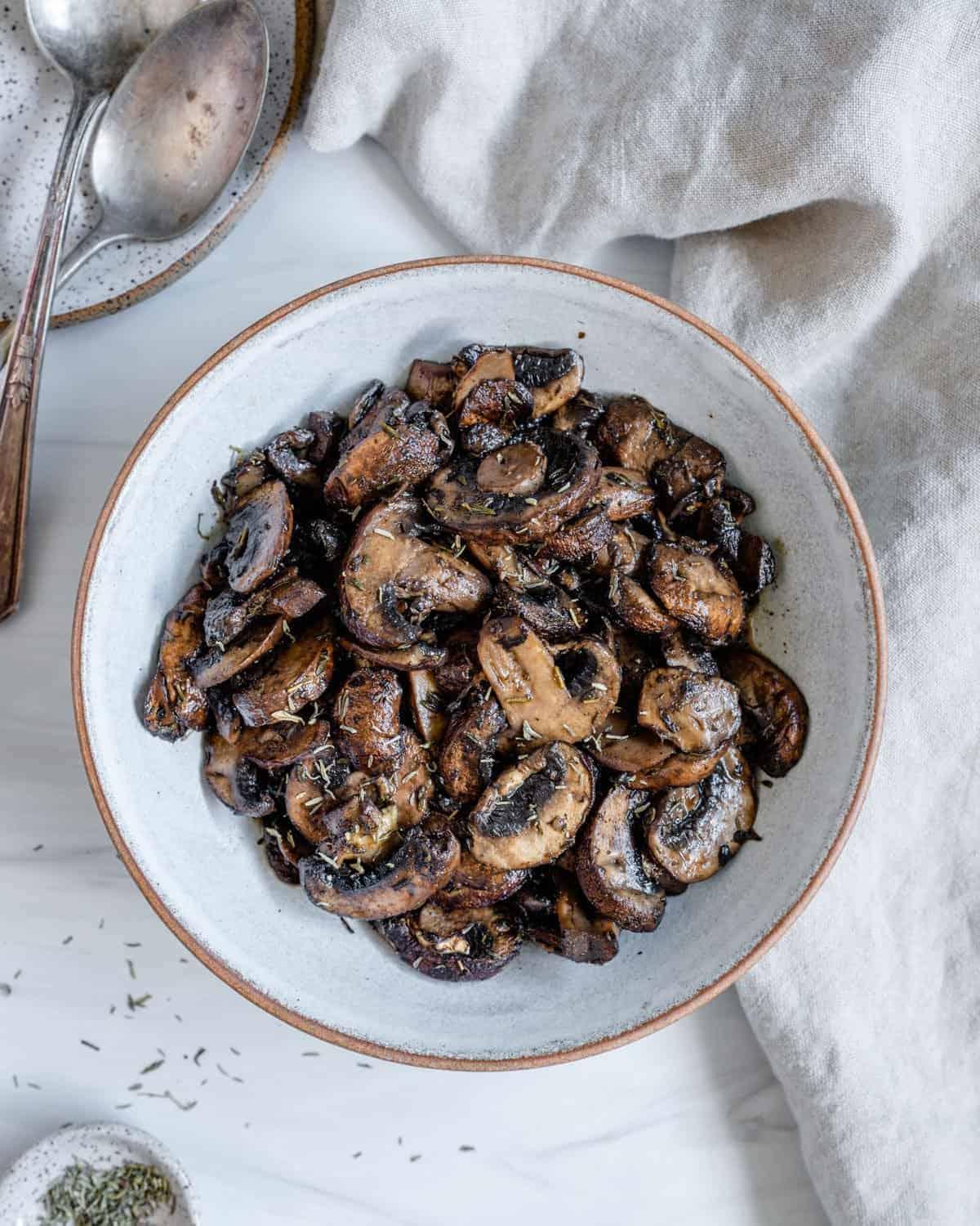 completed simple roasted mushrooms on a white plate against a white background