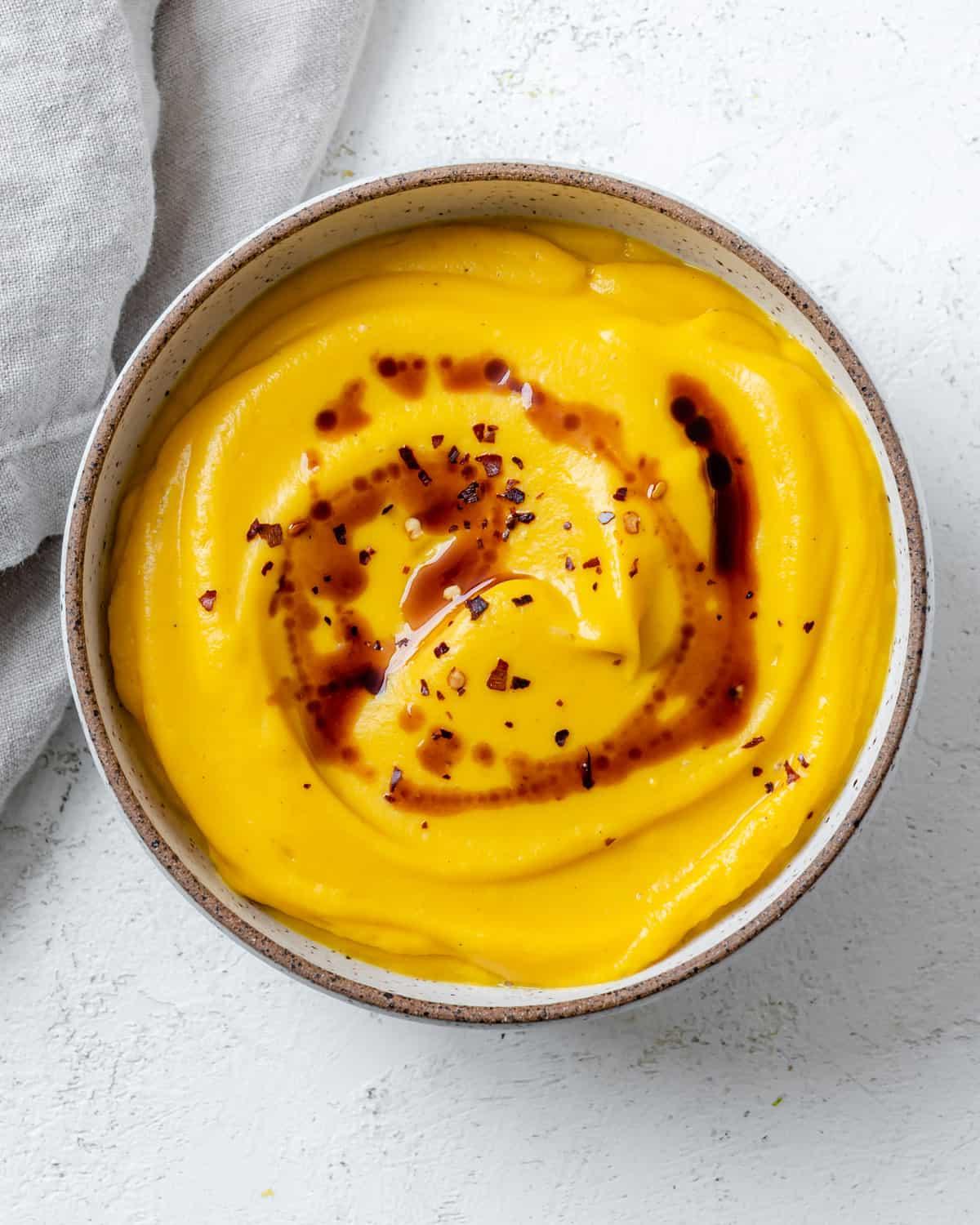 Fertiggestellte einfache vegane Kürbissuppe auf weißem Untergrund