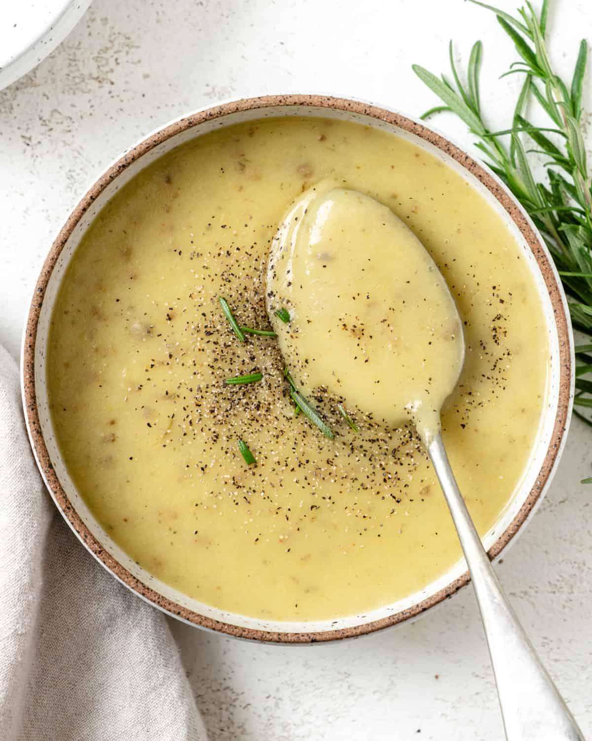 Fertige cremige vegane Kartoffel-Lauch-Suppe in einer Schale vor hellem Hintergrund