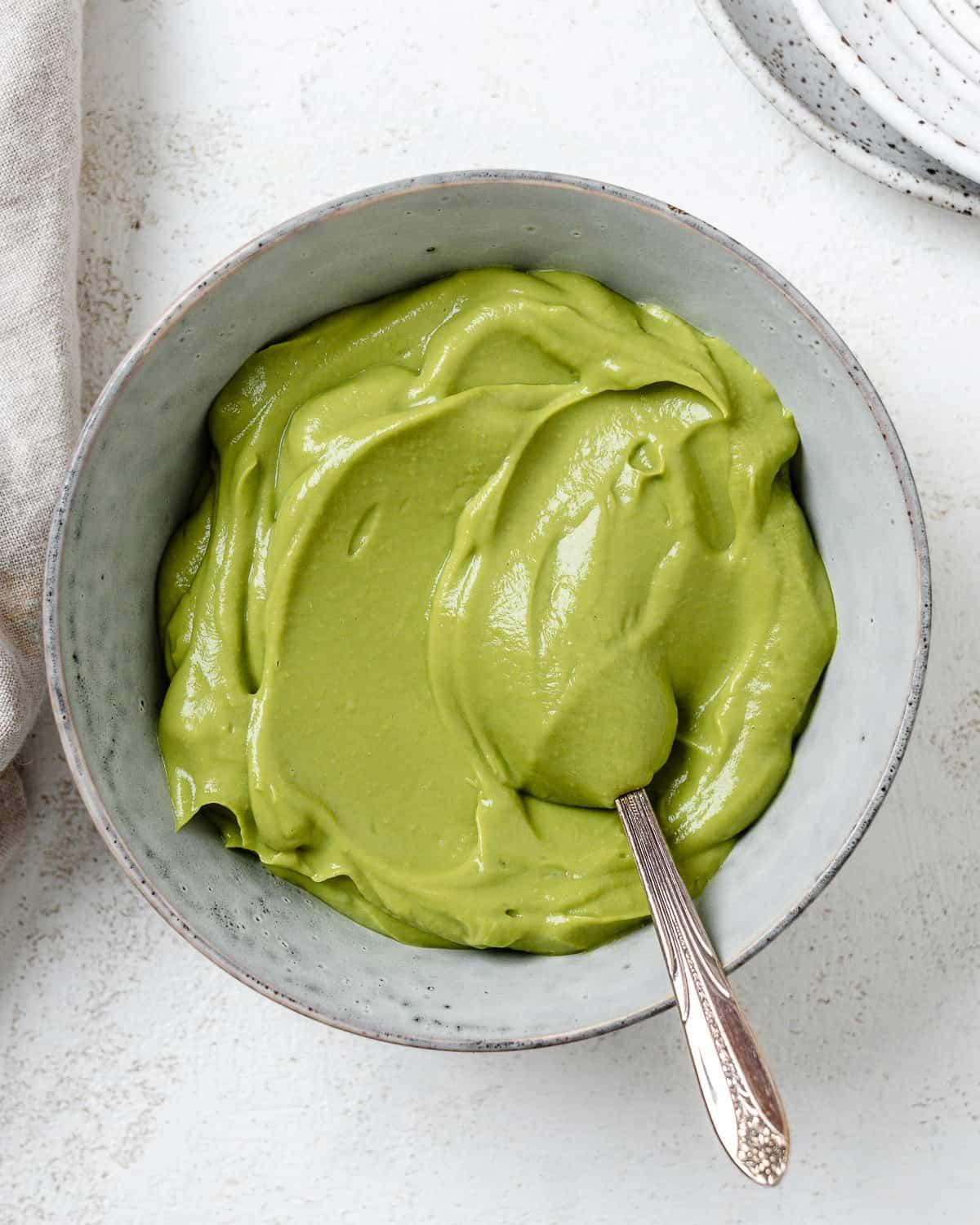 Einfacher Avocado-Aufstrich 2 Fertiger cremiger Avocado-Aufstrich in einer Schale vor hellem Hintergrund