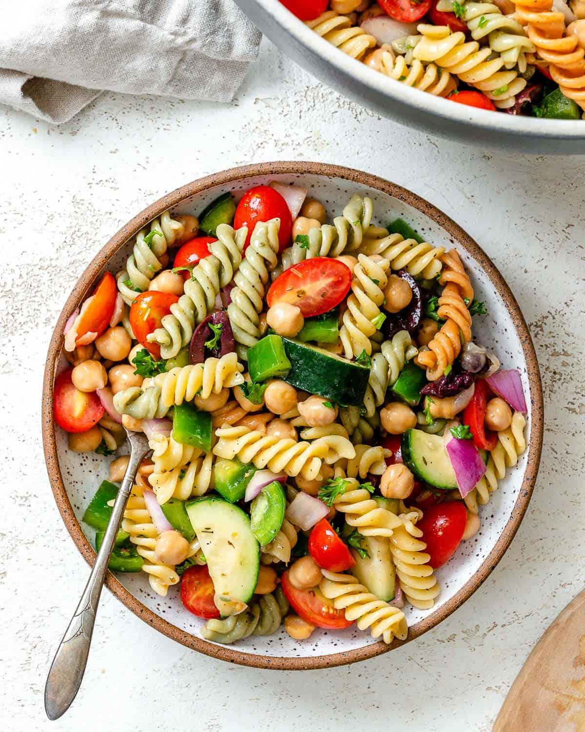 **Mediterraner veganer Nudelsalat** 2 Fertig angerichteter mediterraner veganer Nudelsalat auf weißem Untergrund