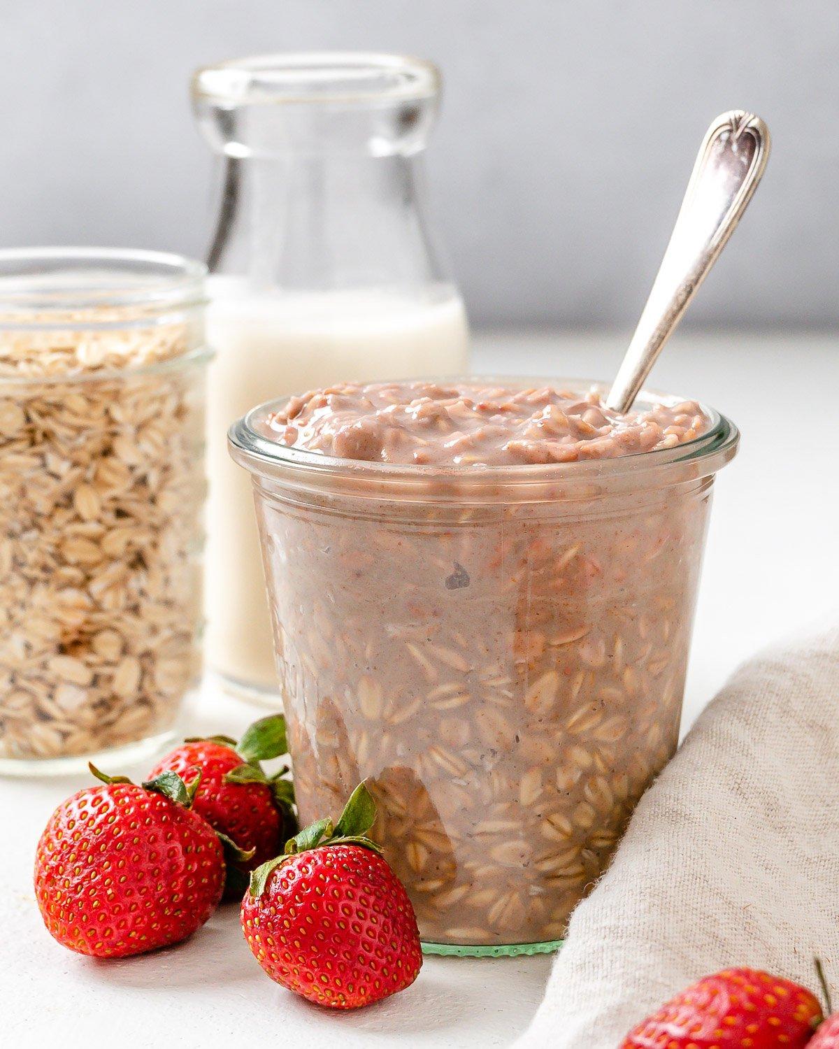 Erdbeer-Overnight-Oats (Vegan) 2 Fertige vegane Erdbeer Overnight Oats in zwei Gläsern mit Erdbeeren im Vordergrund auf einer weißen Oberfläche