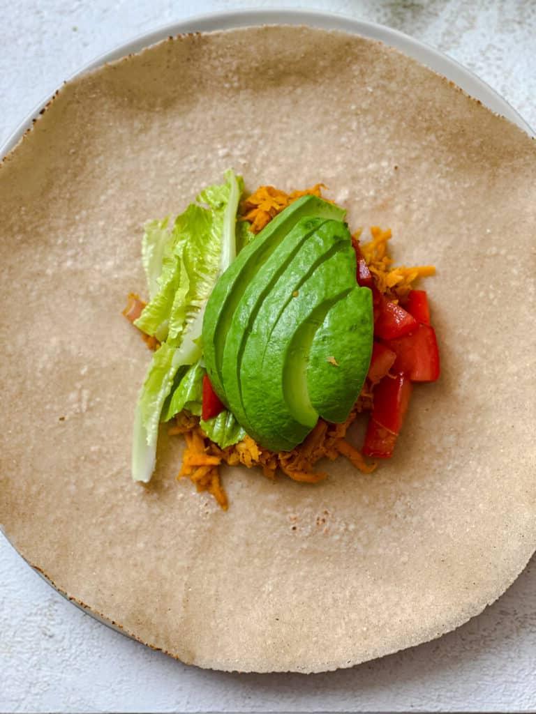 Süßkartoffel-Burritos 11 Süßkartoffelmischung, Salat, Avocado und Tomaten auf Tortilla hinzugefügt