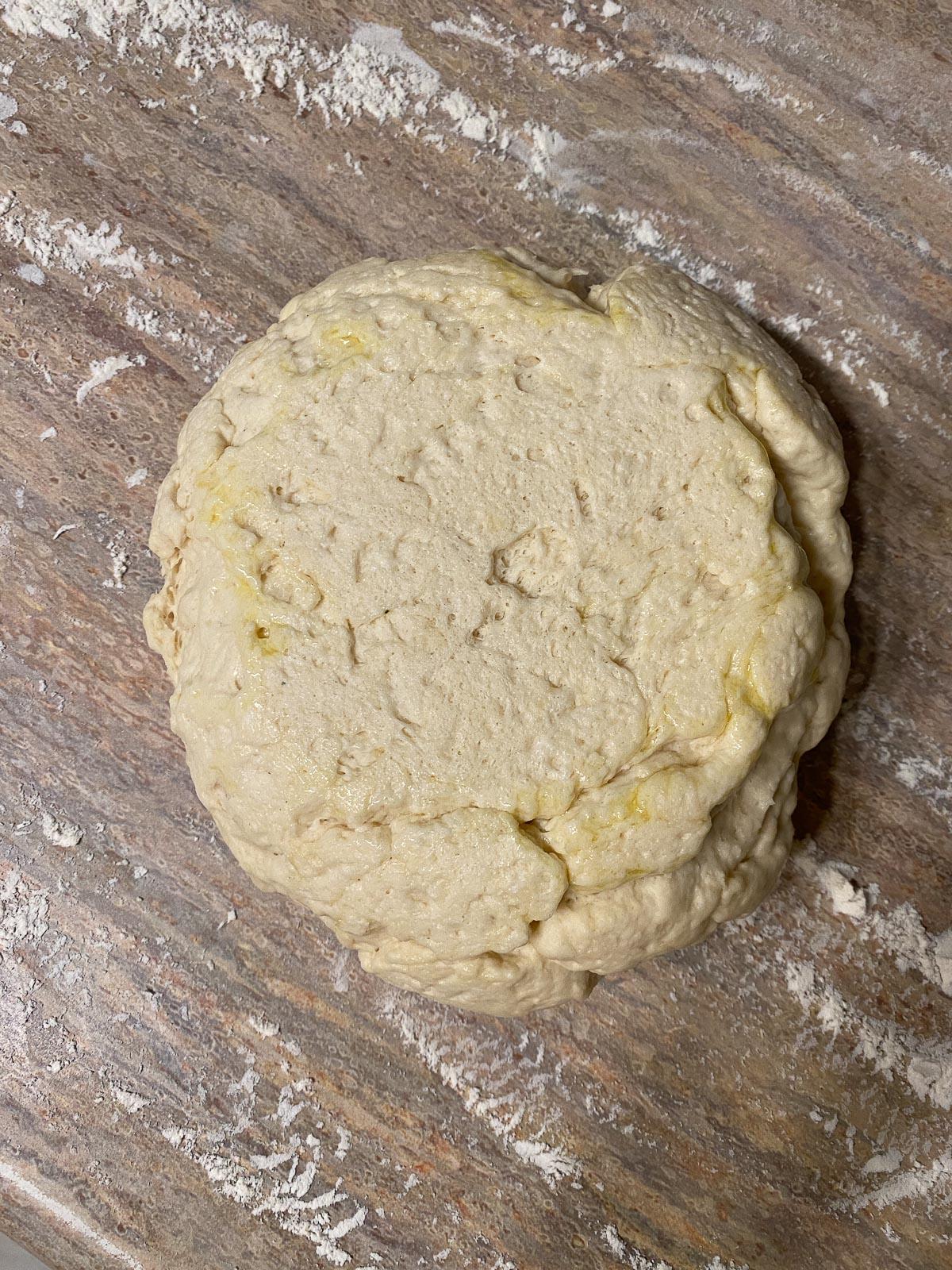 Vegane Pizzaröllchen 10 process of forming flour in a white bowl against a light brown surface