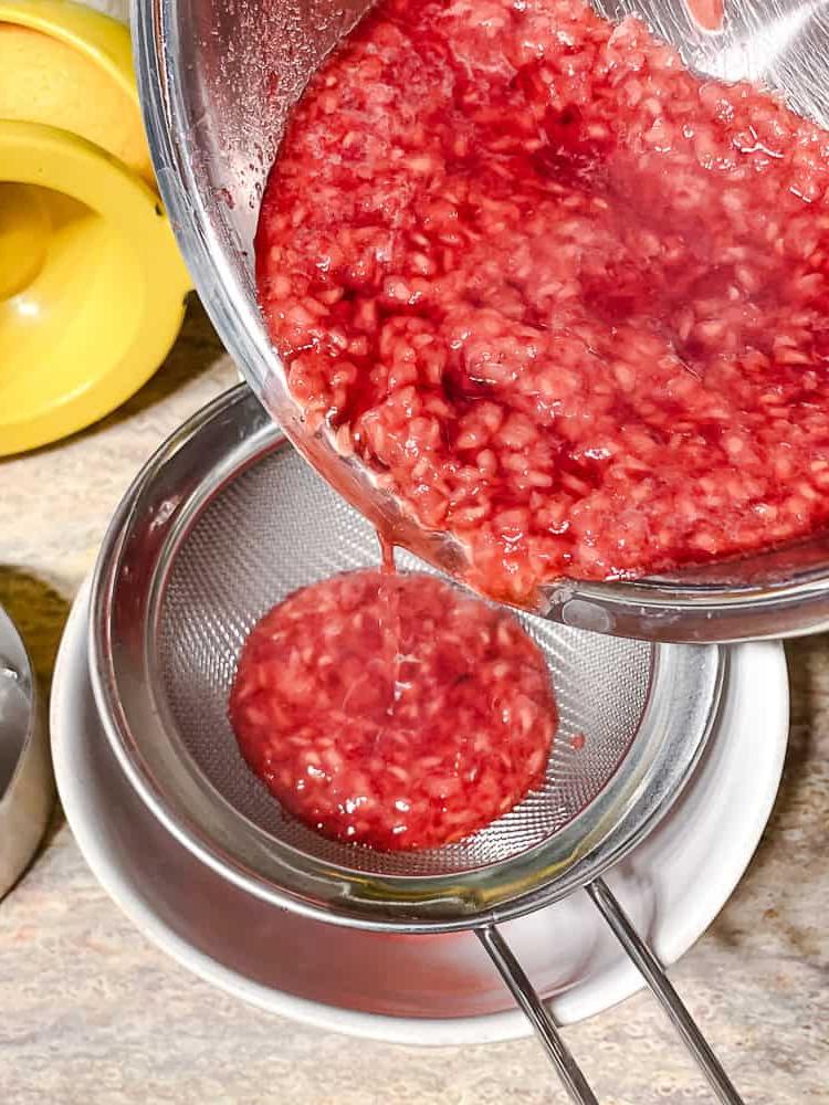 Peach Melba 11 Himbeersauce wird durch ein feines Sieb passiert.