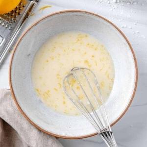 Fertige Zitronenglasur in weißer Schüssel mit Schneebesen