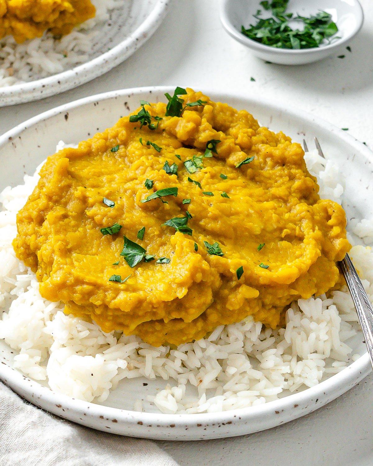 Einfaches gelbes Dal-Rezept 11 Fertiges einfaches gelbes Dal auf Reis in einem weißen Teller vor hellem Hintergrund