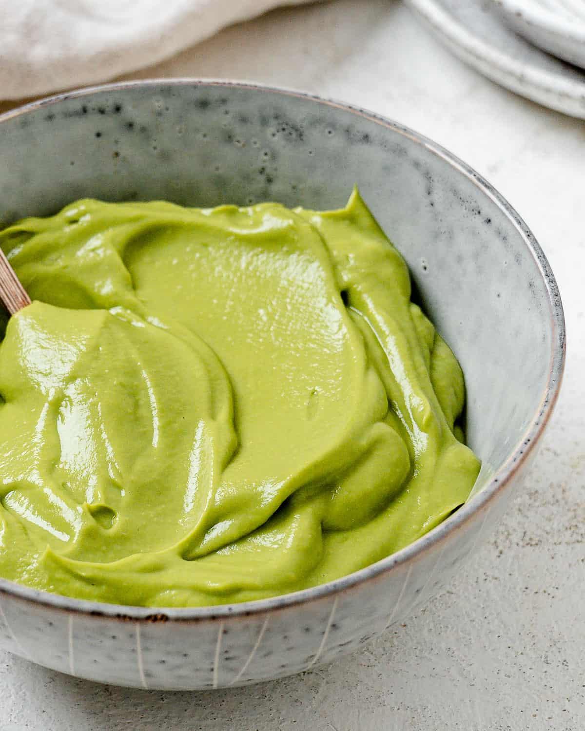 Einfacher Avocado-Aufstrich 11 Fertiger cremiger Avocado-Aufstrich in einer Schale vor hellem Hintergrund