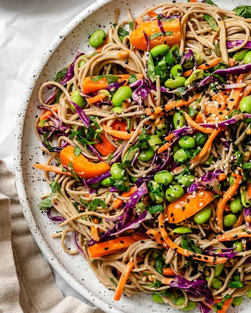 close up on soba noodle salad on a large white serving plate.
