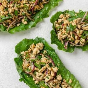 Veganer Tofu-Larb-Salat 12 Drei Portionen Larb Salat auf weißer Oberfläche angerichtet.
