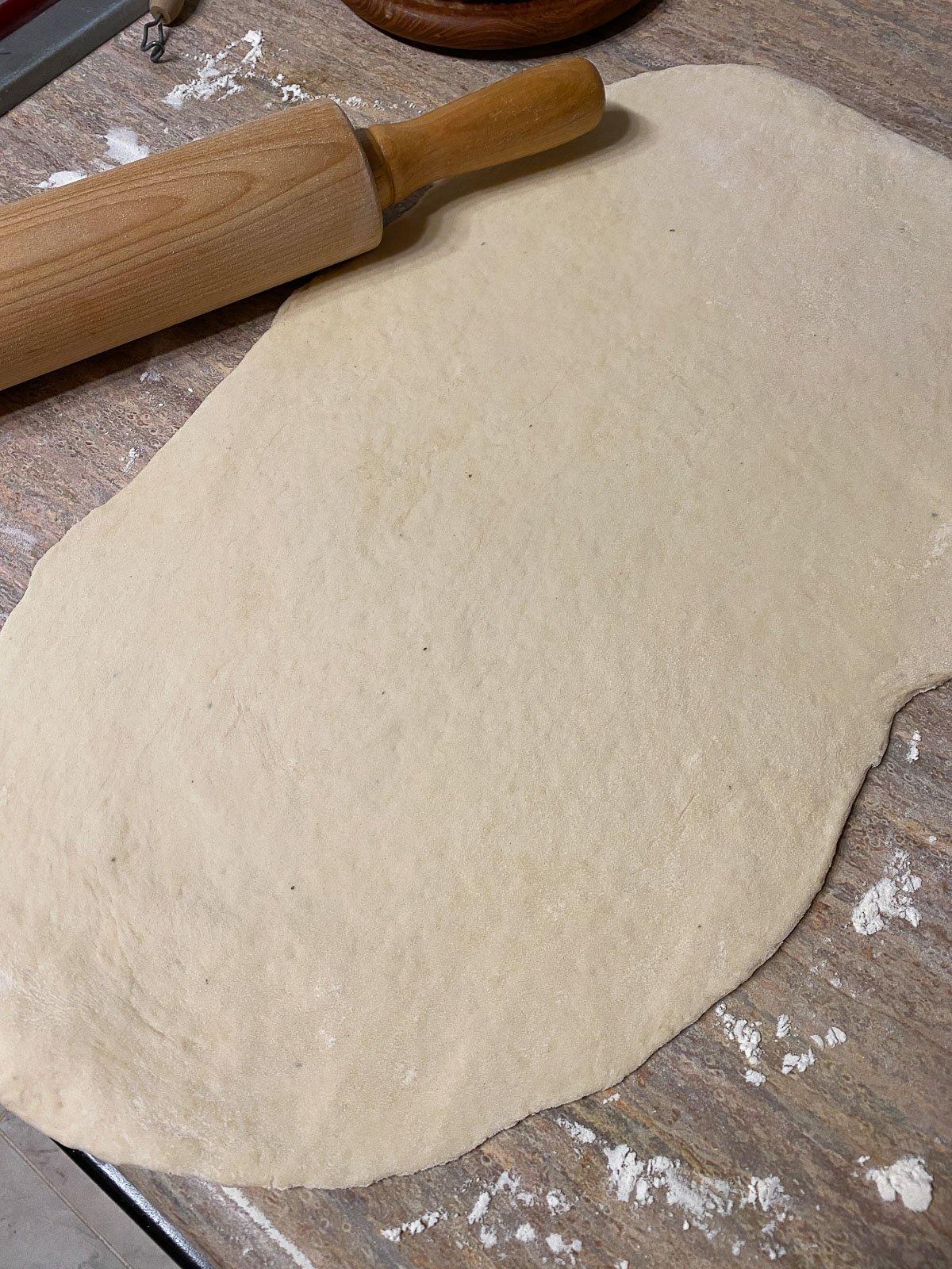 Vegane Pizzaröllchen 11 process of flattening flour in a white bowl against a light brown surface