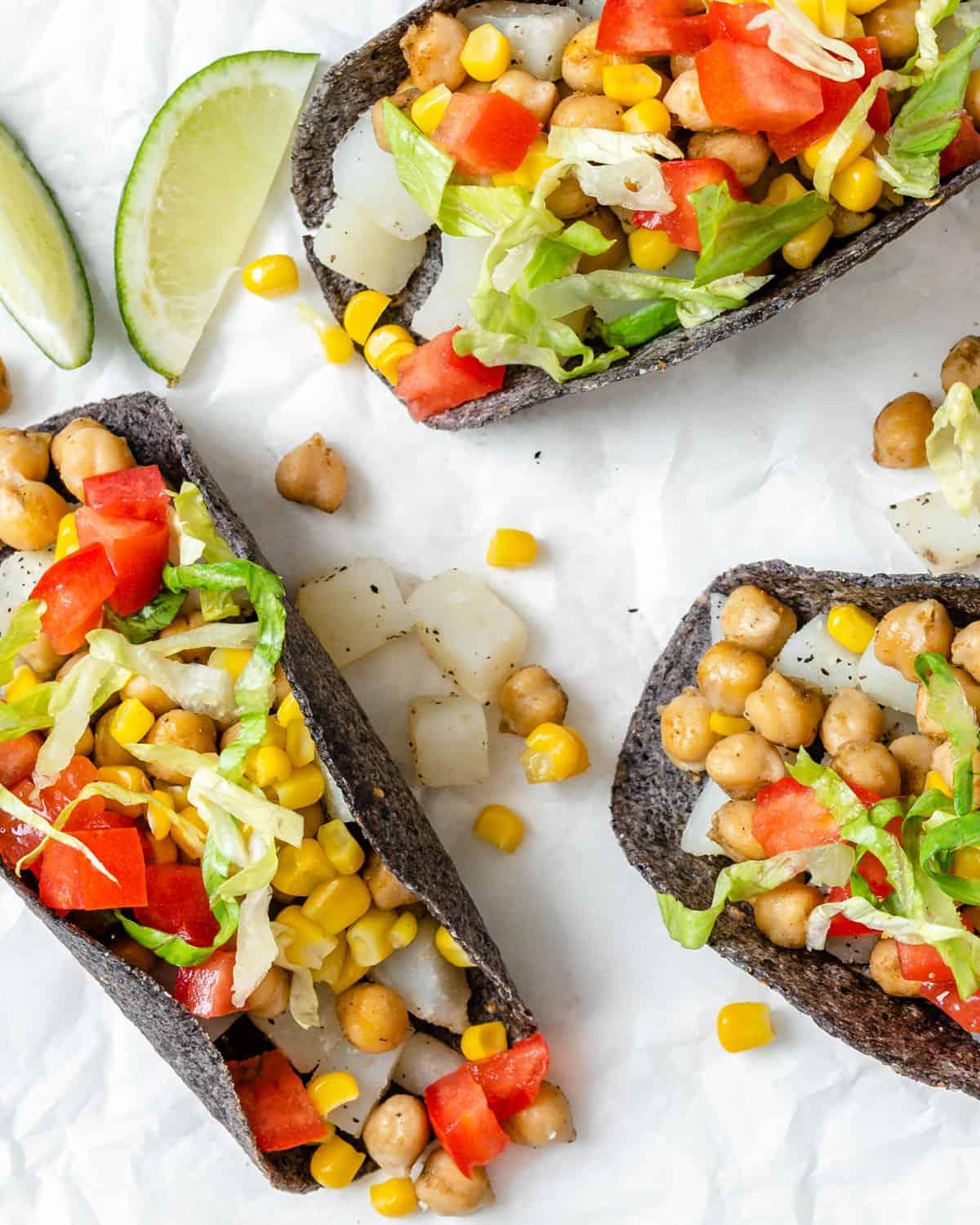 30 einfache vegane Kartoffelrezepte 12 Drei fertige Kartoffel-Kichererbsen-Tacos auf einer weißen Oberfläche