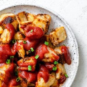 Fertige Patatas Bravas auf einem weißen Teller angerichtet