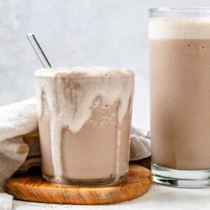 Fertiger Zimt-Hanfsamen-Kaffee-Shake in zwei Gläsern auf hellem Untergrund