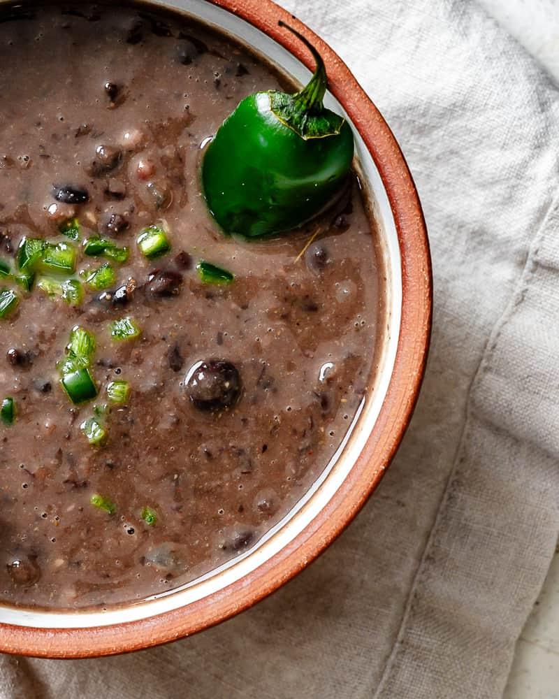 Schwarze Bohnensuppe 12 Nahaufnahme von schwarzer Bohnensuppe mit gewürfelten Jalapeños in einer Schüssel.