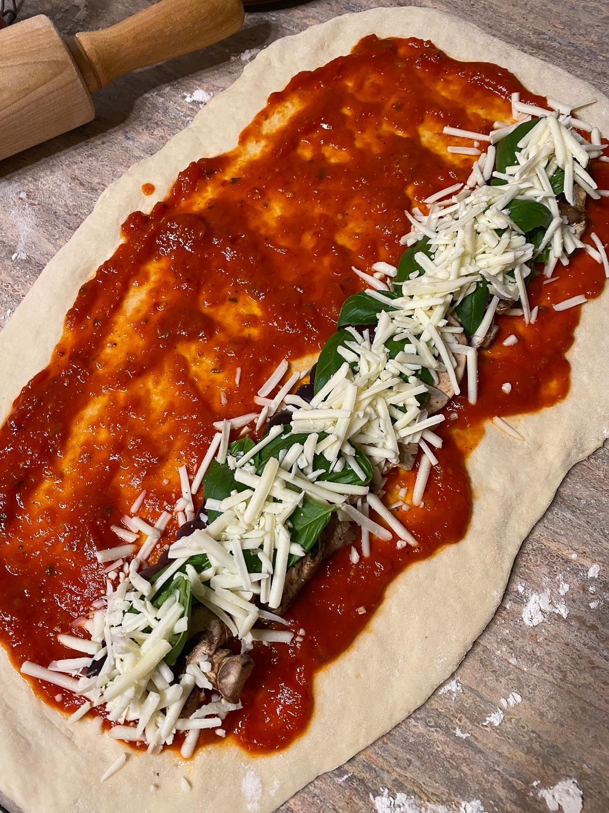 Vegane Pizzaröllchen 12 process of adding basil, cheese, and marinara sauce to flour