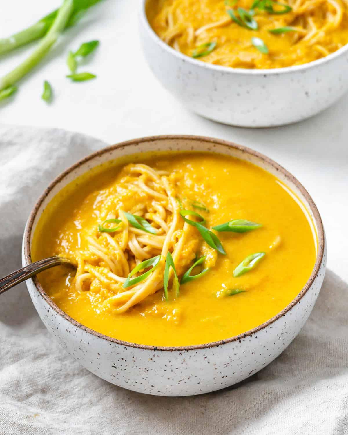Karotten-Curry-Suppe mit Nudeln 13 Fertige Curry-Karotten-Suppe mit Nudeln auf weißem Untergrund