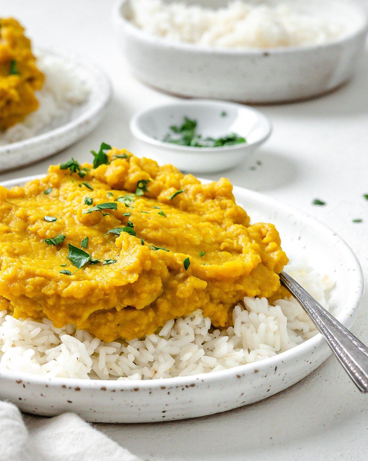 Einfaches gelbes Dal-Rezept 13 Fertiges einfaches gelbes Dal auf Reis in einem weißen Teller vor hellem Hintergrund