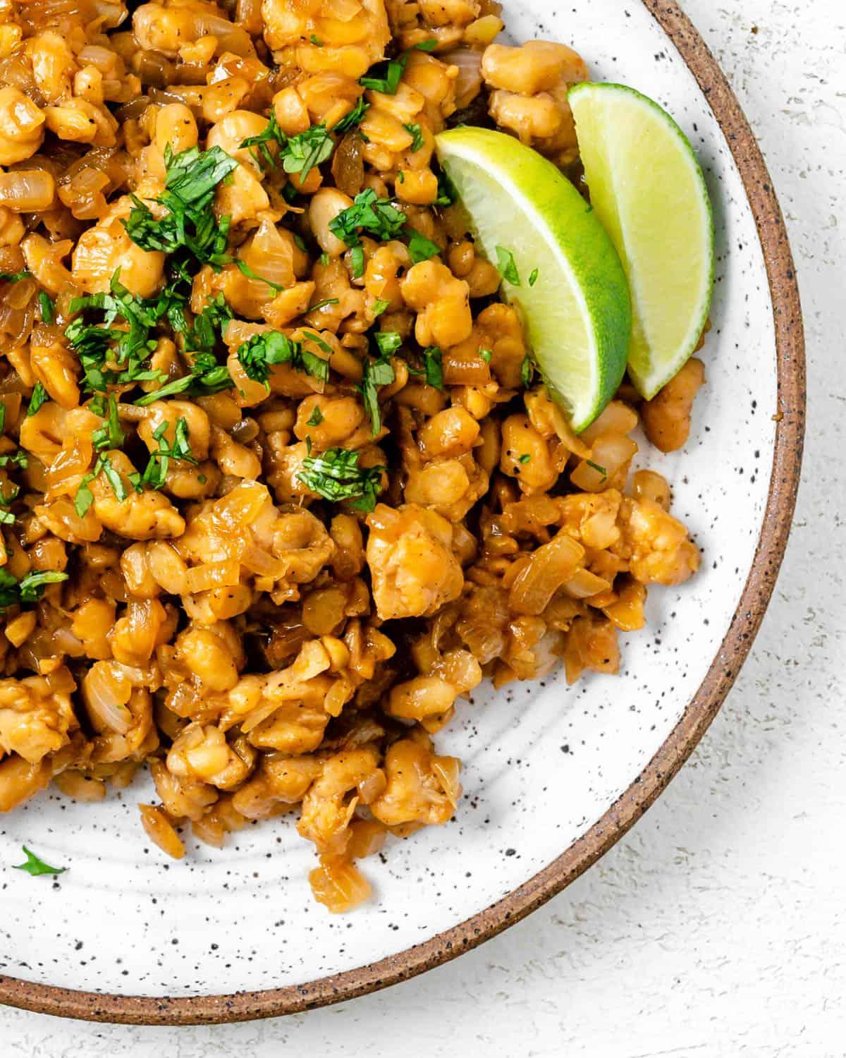Pfannengebratenes Tempeh mit Ingwer-Sojasauce 13 Fertig gebratenes Tempeh mit Ingwer-Soja-Sauce auf einem Teller vor hellem Hintergrund