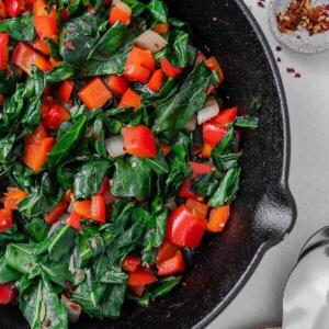 Scharfer Blattkohl 13 completed Spicy Collard Greens in a black pan against a white surface