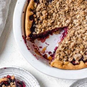 completed Mixed Berry Crumb Pie with a piece plated on a small white plate