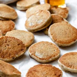 Mehrere fertige einfache vegane Pfannkuchen in verschiedenen Größen auf einer weißen Oberfläche