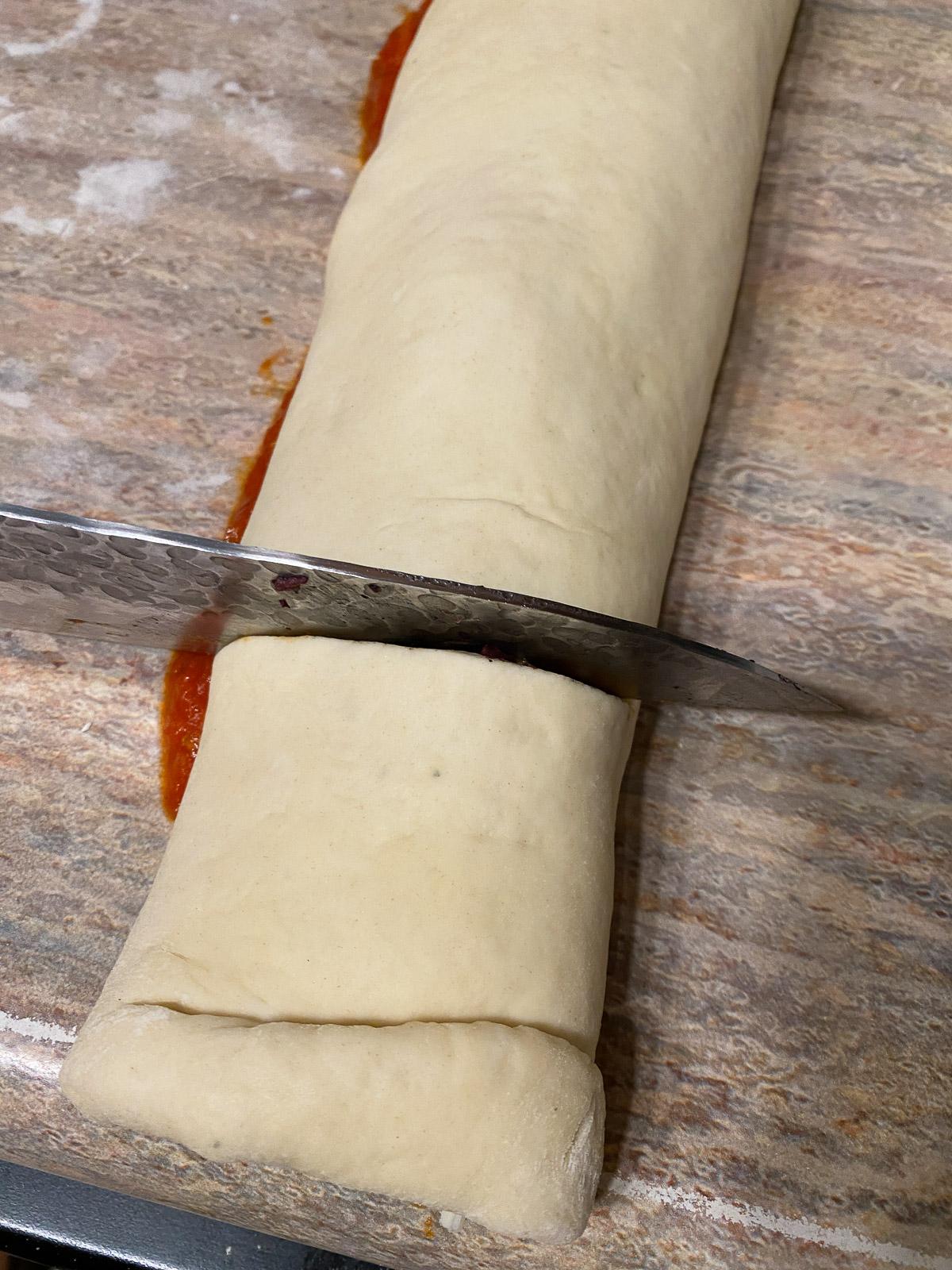 Vegane Pizzaröllchen 14 process of cutting pizza into rolls with a cutting knife