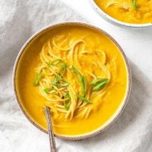 Karotten-Curry-Suppe mit Nudeln 15 Fertige Curry-Karotten-Suppe mit Nudeln auf weißem Untergrund