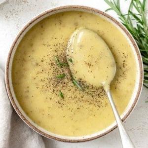 Fertige cremige vegane Kartoffel-Lauch-Suppe in einer Schale vor hellem Hintergrund