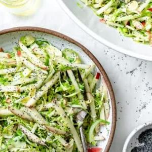 Gehobelter Rosenkohlsalat mit Äpfeln 15 Fertiger Rosenkohl-Krautsalat mit Äpfeln auf einem hellen Teller angerichtet