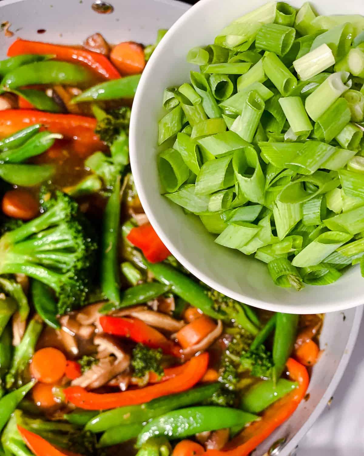 Einfaches Wok-Gemüse 17 Prozessaufnahme des Hinzufügens von Frühlingszwiebeln zur Pfanne