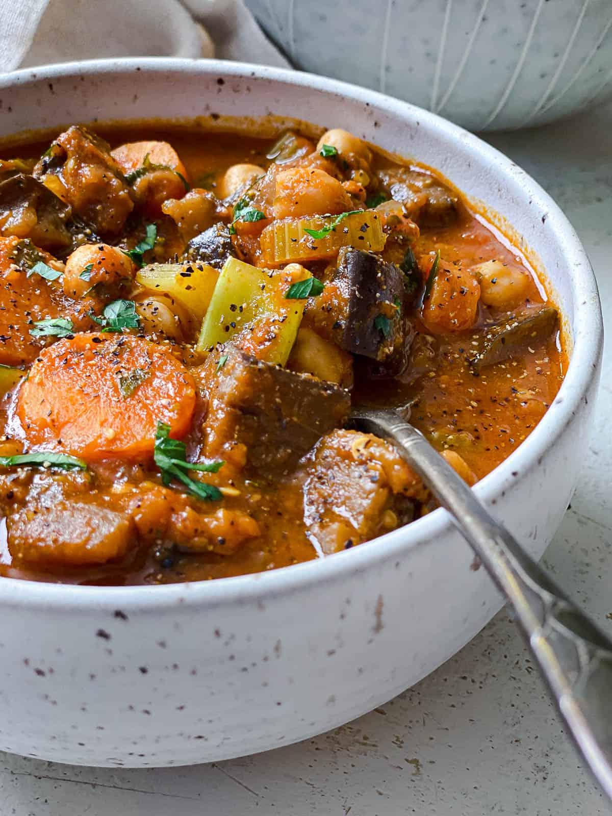 Fertig gestellter Auberginen-Eintopf mit Tomaten und Kichererbsen auf einer weißen Oberfläche