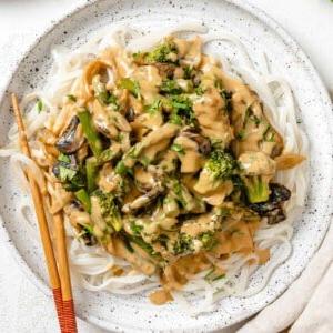 Cremige Reisnudelpfanne 19 Fertiges veganes Reisnudelrezept mit Tahini-Pfannen-Sauce auf einem weißen Teller mit Essstäbchen