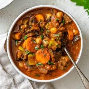 Fertig gestellter Auberginen-Eintopf mit Tomaten und Kichererbsen auf einer weißen Oberfläche