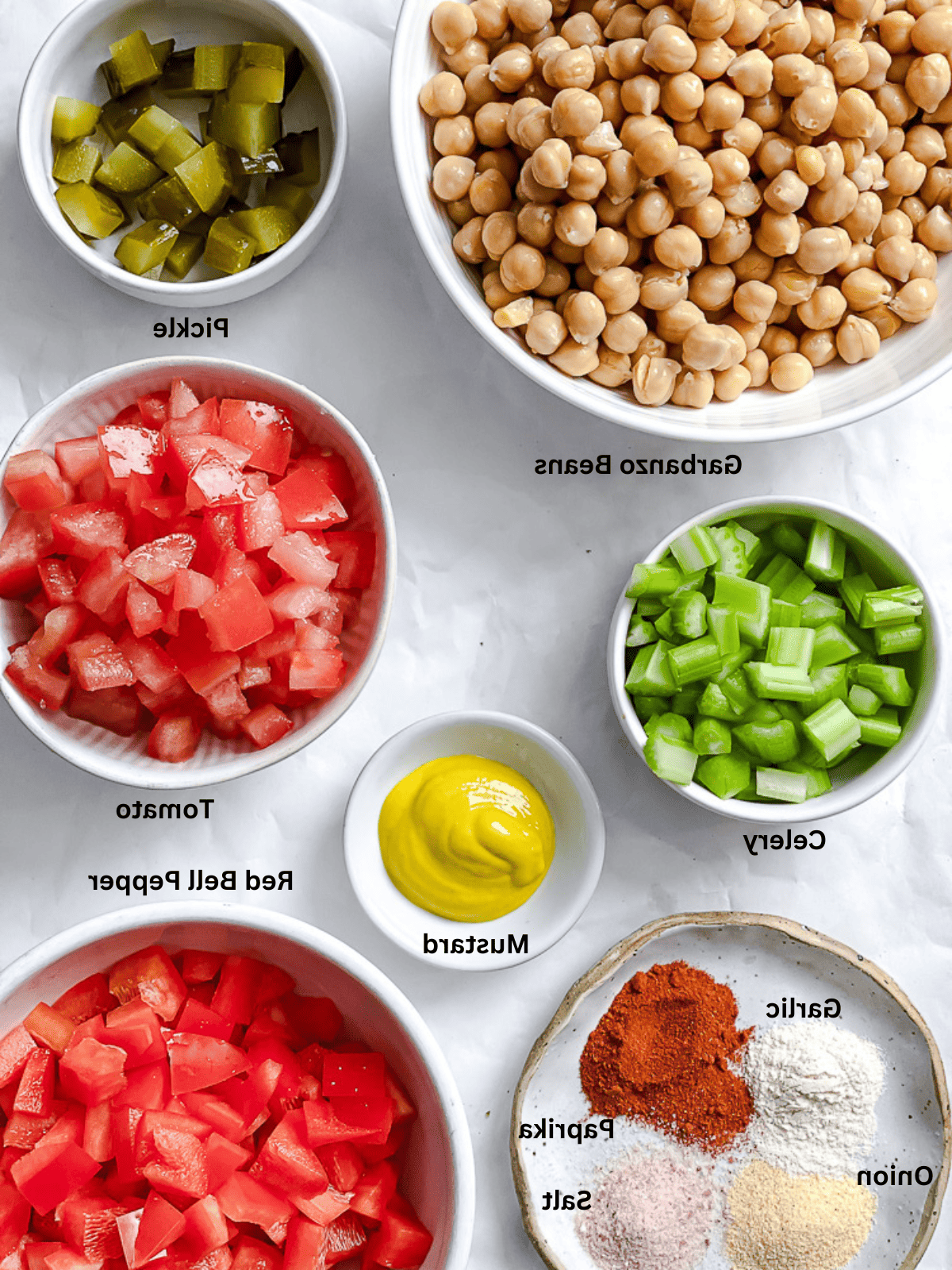 Veganer Kichererbsensalat 3 Zutaten für veganen Kichererbsensalat in kleinen weißen Schüsseln mit Beschriftungen.