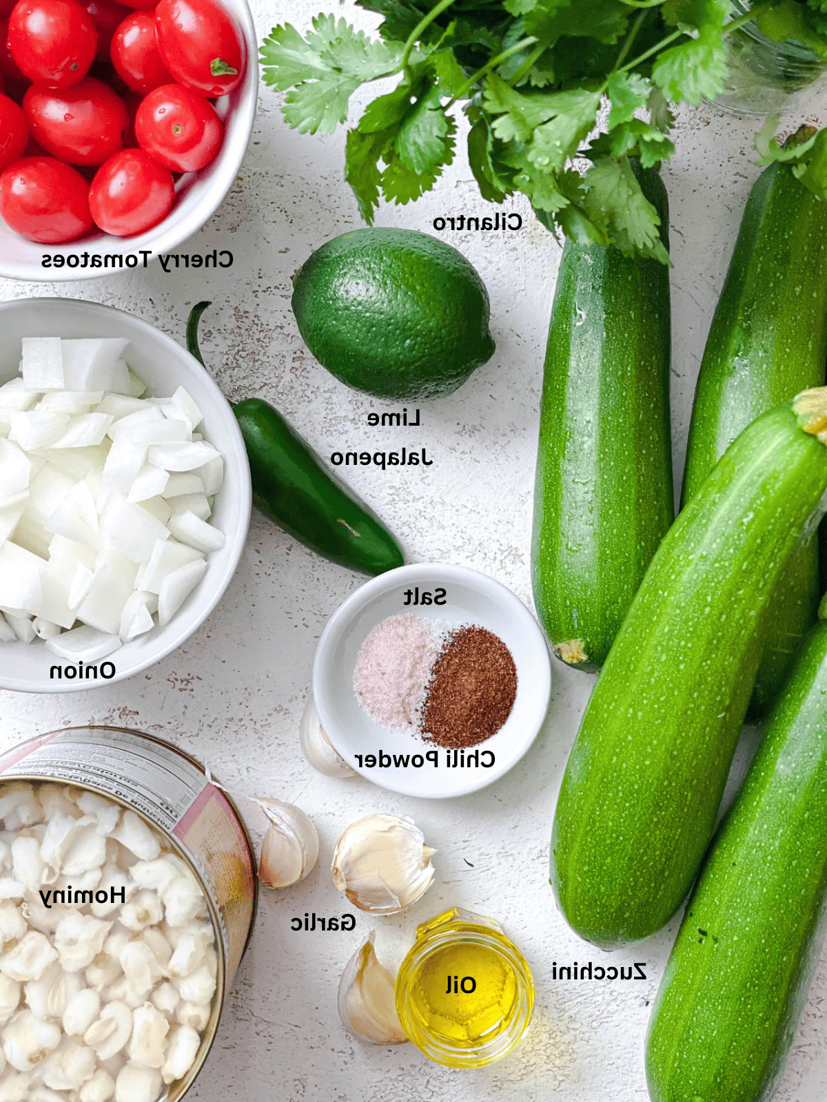 Sommer-Zucchini und geschälter Mais 3 ingredients for Summer Zucchini and Hominy measured out on a white surface