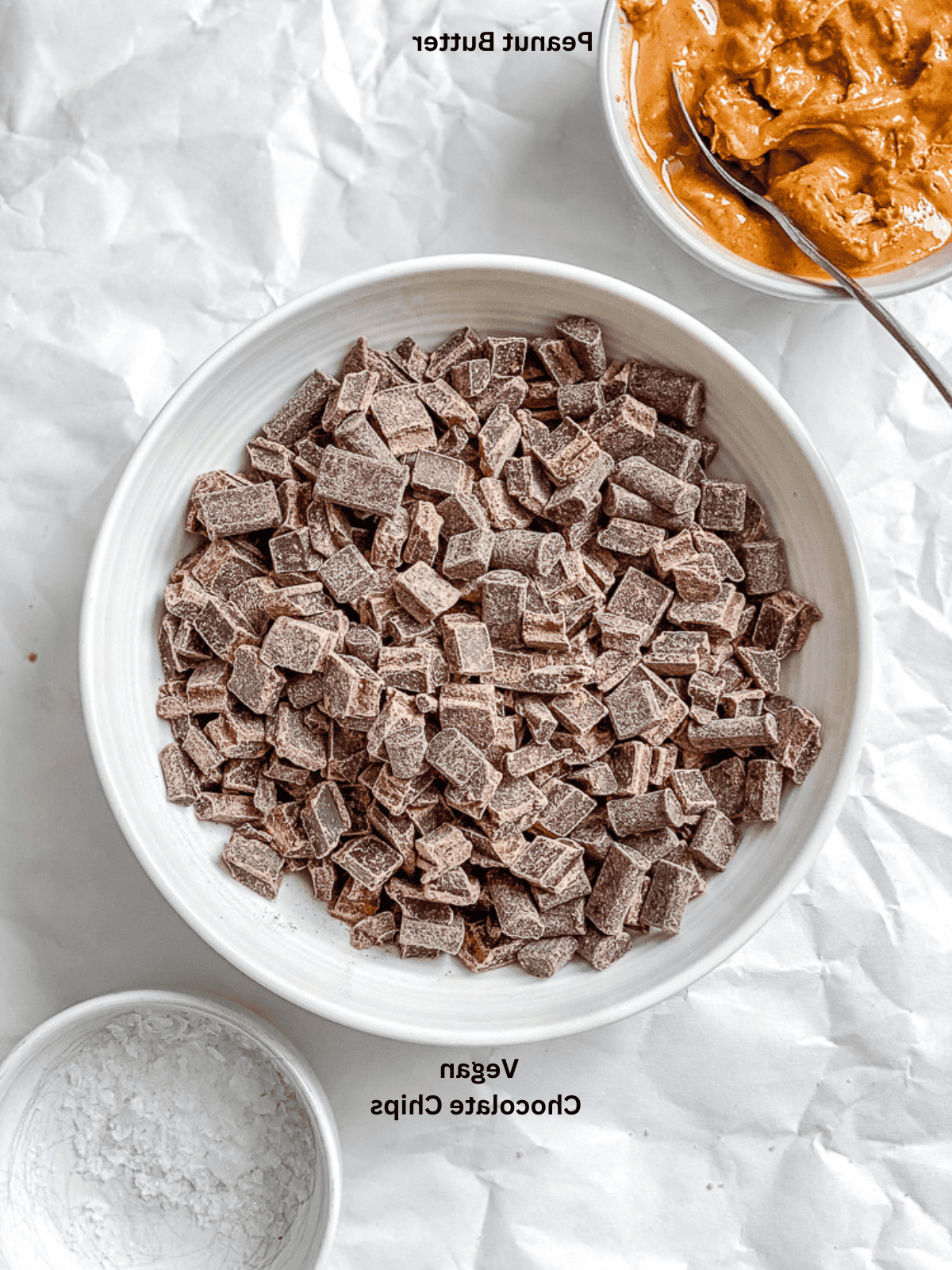 Zutaten für vegane Erdnussbutter-Cups abgemessen auf einer weißen Oberfläche.