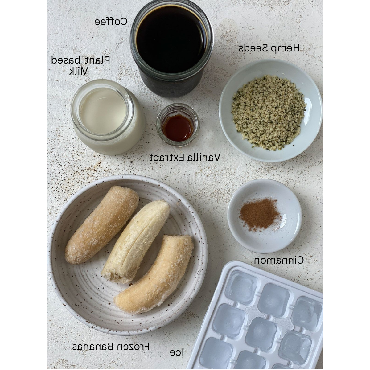 Zutaten für Zimt-Hanfsamen-Kaffee-Shake abgemessen auf weißem Untergrund
