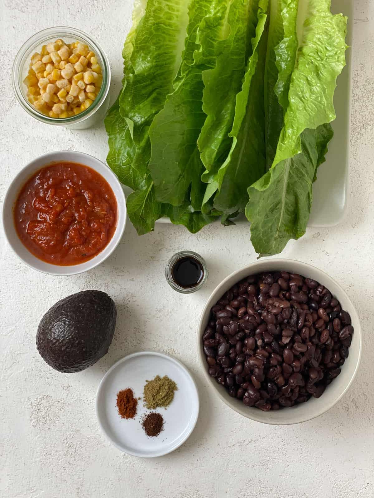 Vegane Schwarze-Bohnen-Salatwickel 3 ingredients for Vegan Black Bean Lettuce Wraps measured out against a white surface