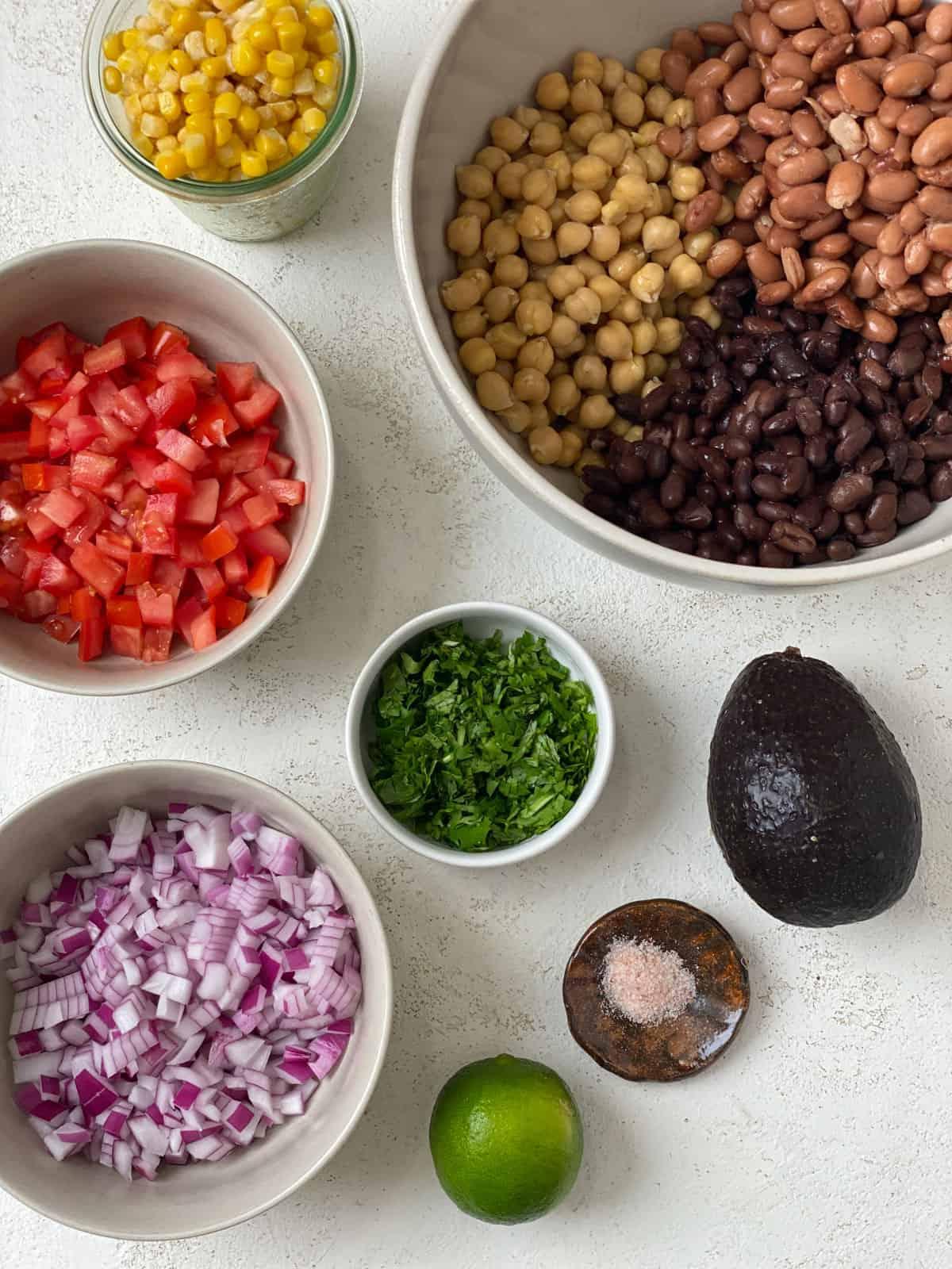 Zutaten für Texas Caviar [Avocado-Mais-Bohnen-Salat] vor weißem Hintergrund