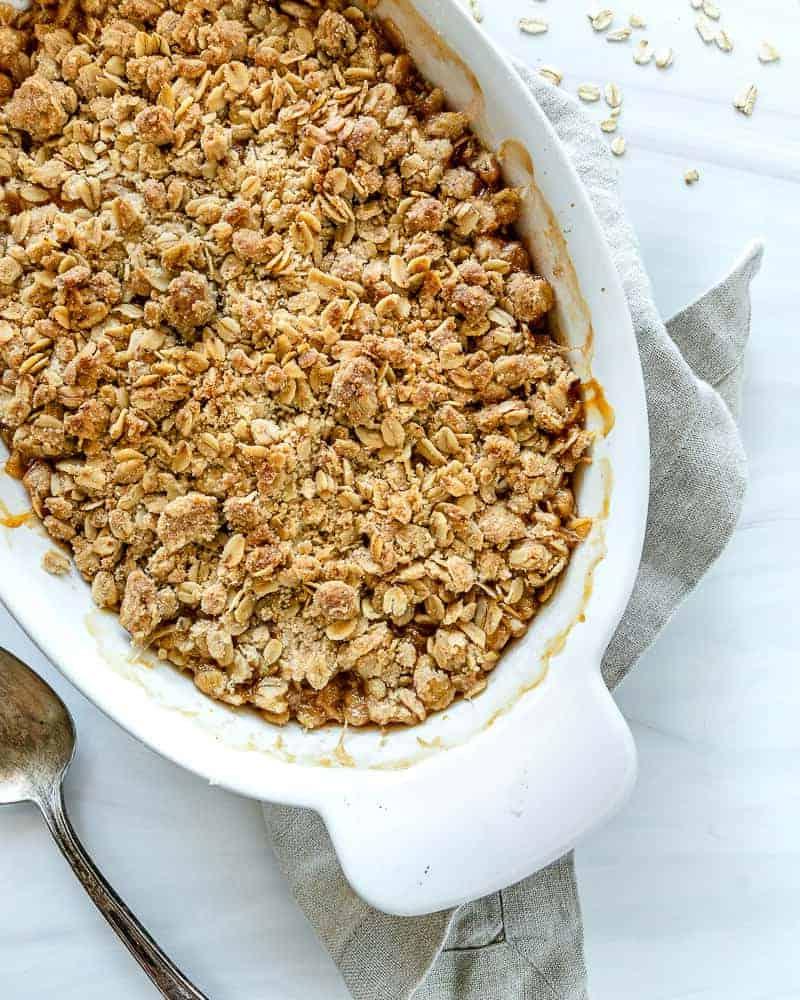 Aprikosen Crumble Zubereitung Eine weiße Schale mit Aprikosen-Crisp auf weißem Hintergrund, bereit zum Servieren.