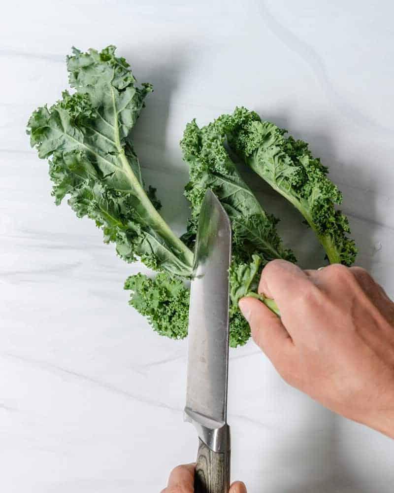 Curly Kale Removing Stem on a Marble Surface 
