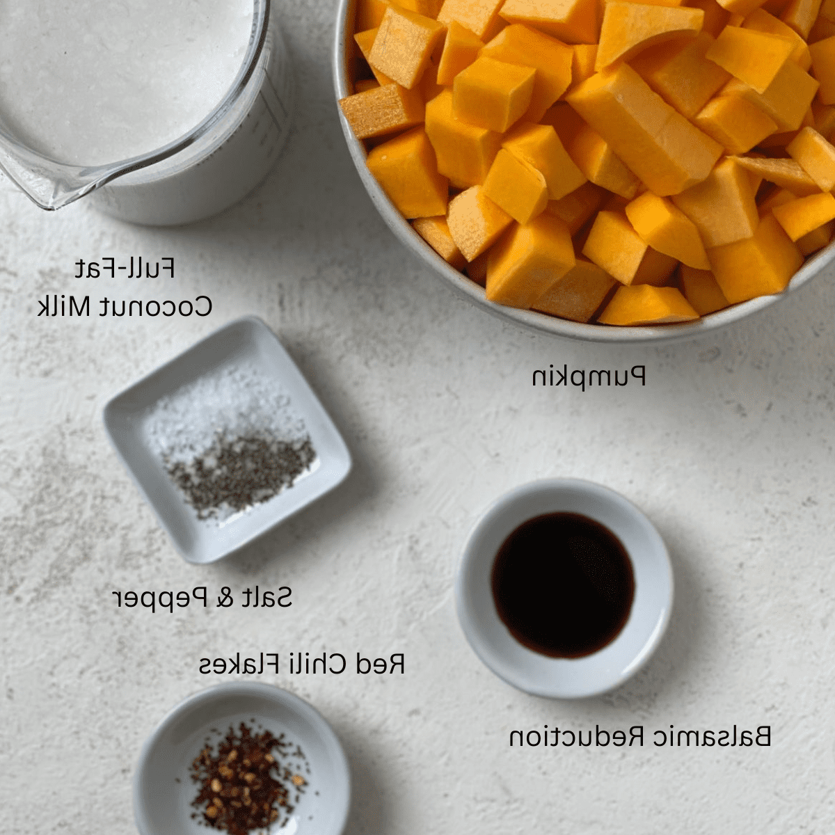Zutaten für einfache vegane Kürbissuppe abgemessen auf weißem Untergrund