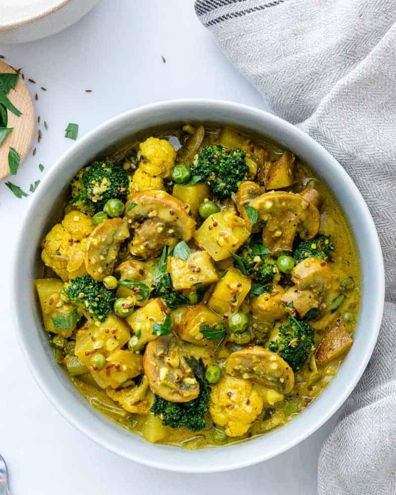30 einfache vegane Kartoffelrezepte 21 Perfektes Kartoffel-Erbsen-Kokos-Curry in einer weißen Schüssel auf weißem Hintergrund